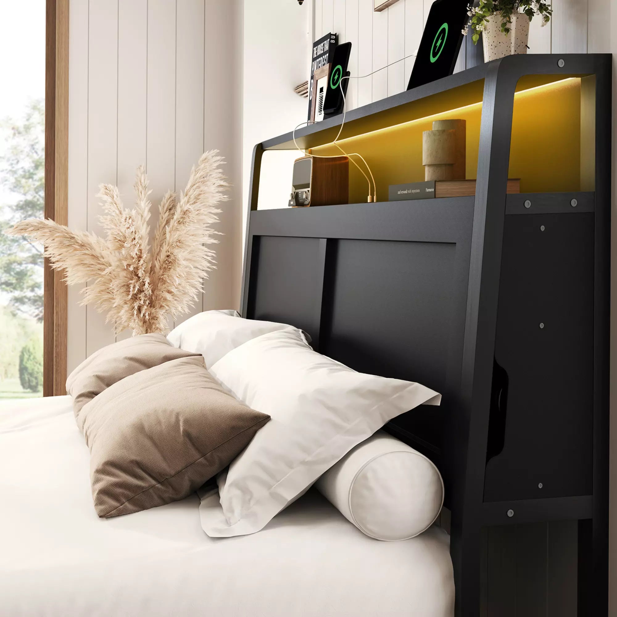 Black headboard with pillows and a plant in a room with a window.