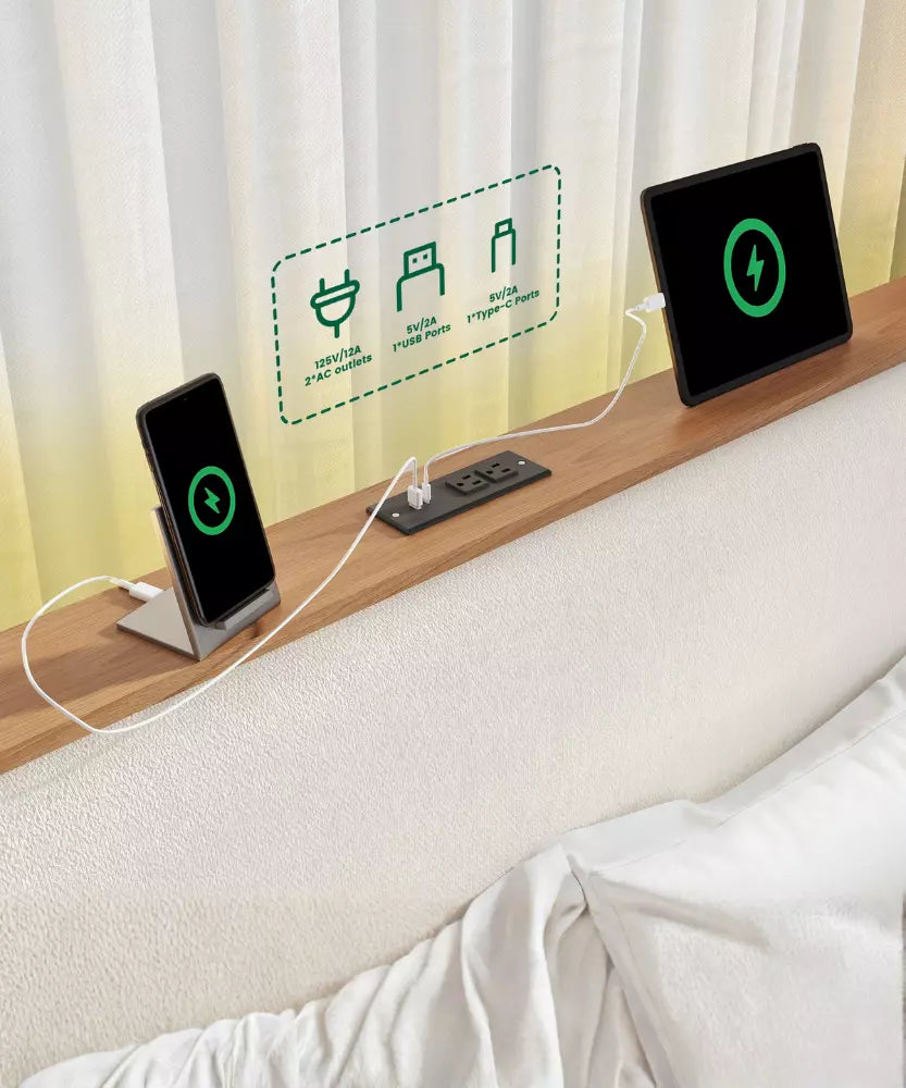 Two electronic devices charging on a wooden surface with a curtain in the background.